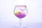 Yellow and violet paints fall in a wineglass with water