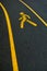 Yellow walking trail symbol on black asphalt road