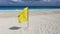 Yellow warning flag indicating adverse conditions or dangerous rip currents on a tropical white sand beach