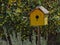 Yellow weathered bird house in a home garden