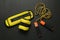 Yellow weighting agents and skipping rope on yoga mat, flat lay