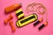 Yellow weighting agents and sport equipment on pink background, flat lay