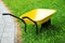 Yellow wheelbarrow on green grass. Gardening tool
