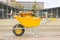 Yellow wheelbarrow with stone cutter on new pavement