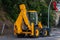 Yellow wheeled excavator standing on the side of the road