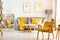Yellow wooden armchair in bright living room interior with grey