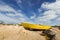 Yellow wooden boat stranded on stony shore with dramatic cloudy sky after storm