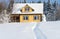 Yellow wooden house and snowman on forest background in winter sunny day