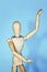 Yellow wooden maniken is dancing and doing poses on blue background