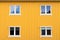 Yellow wooden wall pattern with four windows, outdoors, Norway