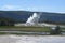 YELLOWSTONE NATIONAL PARK, WYOMING - JUNE 8, 2017: Firehole River Winds in Front of Erupting Castle Geyser in Upper Geyser Basin