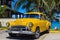 Yellwow american Oldtimer parked under palms near the beach in Varadero Cuba - Serie Kuba 2016 Reportage