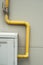 Yelow pipes and gas meter on gray wall