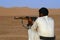 Yemeni man aim with kalashnikov machine gun in the desert, Hadramaut valley, Yemen.