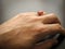 Yemeni red akeek agate stone. Male hand with ring on ring finger with dark background