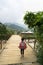 Yen Bai, Vietnam - Sep 18, 2016: Vietnamese Hmong ethnic minority girl walking home on old small chain wooden bridge from school w