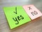 Yes or no question message on sticky notes with focus on yes on wooden table background