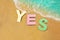 Yes sign floating in water near beach sand edge