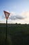 Yield Sign on Country Road at Sunset with Wind Generator in Background