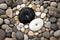 yin yang symbol in black and white pebbles on a sandy beach