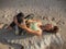 Yoga on the beach. Beautiful woman lying on the sand  doing stretching exercise for hips and legs. Slim body. Healthy spine. Bali