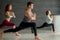 Yoga beginners exercising against grey wall, doing yoga or pilates posture.