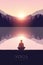 Yoga for body and soul meditating person silhouette by the lake with mountain landscape