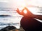 Yoga concept. Closeup woman hand practicing lotus pose on the beach at sunset