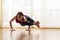 Yoga Concepts. Caucasian Woman Practicing Yoga Exercise Indoors At Bright Afternoon. Sitting in Ashtavakrasana Pose During