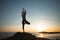 A yoga female perform exercises on a sea beach during a beautiful sunset.