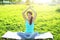 Yoga girl meditates sitting on grass pose lotus in summer