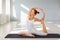 Yoga girl. A woman in white sportswear is practicing yoga balance in a gray room.