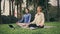 Yoga girls lotus pose sitting on grass. Serene ladies turning tablet meditating