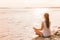 Yoga healthy woman meditating on morning sunrise by the lake. Beach meditation wellness girl enjoying summer sunshine