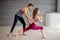Yoga male teacher correcting female student performing Warrior Pose in studio