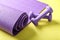 Yoga mat with dumbbells on color background