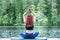 Yoga meditation in lotus pose by Young yogi  girl  on the pier of a beautiful lake.  Concept of healthy life and natural balance