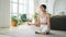 Yoga mindfulness meditation. Young healthy woman practicing yoga in living room at home. Woman sitting in lotus pose