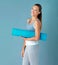 Yoga is my favourite pasttime. Studio portrait of a healthy young woman holding an exercise mat against a blue