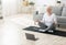 Yoga online. Relaxed senior woman meditating in front of laptop at home