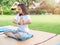 Yoga in park. Asian woman wearing glasses doing yoga, hand exercises outdoor on cushion on mat on the lawn