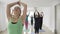 Yoga pilates class doing standing and stretching exercises using mats for floor in a bright fitness studio in slow motion -