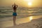 Yoga pose. Woman standing on the beach, practicing yoga. Young woman raising arms with namaste mudra during sunset golden hour.