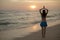 Yoga pose. Woman standing on the beach, practicing yoga. Young woman raising arms with namaste mudra during sunset golden hour.