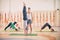 Yoga practice, instructor helping student to do handstand in class, Adho Mukha Vrikshasana, Downward facing Tree Pose, group of pe