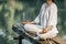 Yoga Retreat. Peaceful Young Woman Sitting in Lotus Position and Meditating by the Lake