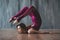 Yoga scorpion pose. Fit sporty girl is stretching. Young beautiful gymnast woman in a jumpsuit doing gymnastic exercises