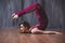 Yoga scorpion pose. Fit sporty girl is stretching. Young beautiful gymnast woman in a jumpsuit doing gymnastic exercises