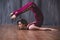 Yoga scorpion pose. Fit sporty girl is stretching. Young beautiful gymnast woman in a jumpsuit doing gymnastic exercises