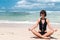 Yoga in the sea or ocean beach. Girl meditating in lotus pose on the tropical island Bali, Indonesia.. Healthy lifestyle